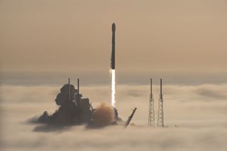 A used SpaceX Falcon 9 rocket carrying 53 Starlink internet satellites launches through a fog layer from a pad at Cape Canaveral Space Force Station in Florida on Nov. 13, 2021.