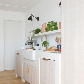 White kitchen with textured cabinetry, Belfast sink and wall lighting