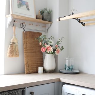 utility room with a ceiling hung traditionalairervase with flowers and a peg rail shelf