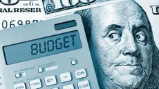 A calculator that says "budget" sitting on top of a hundred dollar bill. Benjamin Franklin's eyes are looking suspiciously at the calculator.