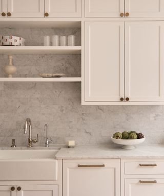 A white, minimalist kitchen with open shelving and stone backsplash