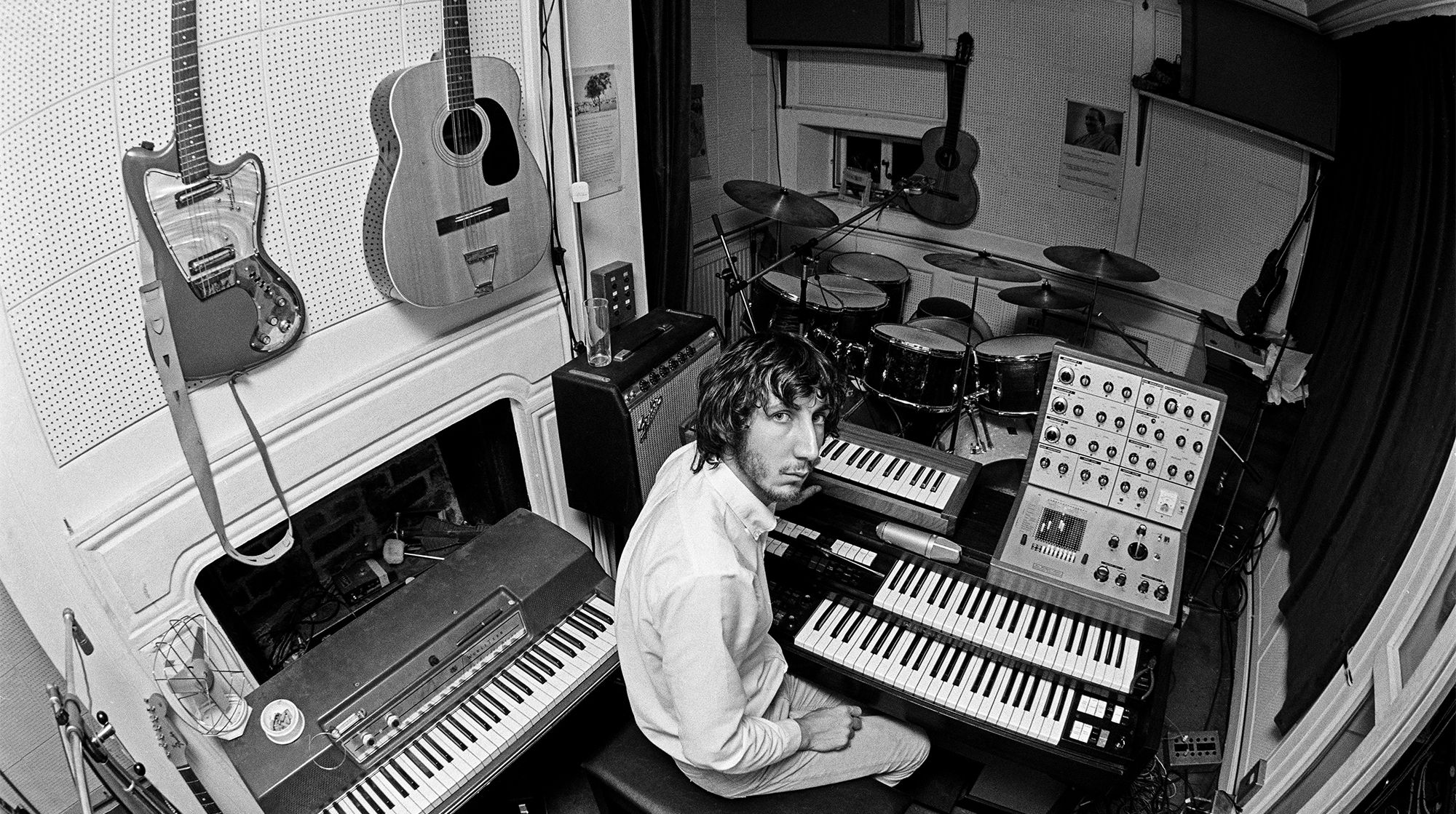 Pete Townshend of The Who, in the recording studio at his home in Twickenham, London, 1970. On the wall (left) are a Coral Hornet electric guitar and a Harmony Sovereign 12-string acoustic. On the right is an EMS VCS3 mk1 synthesizer resting on a Lowrey Berkshire Deluxe TBO-1 organ.