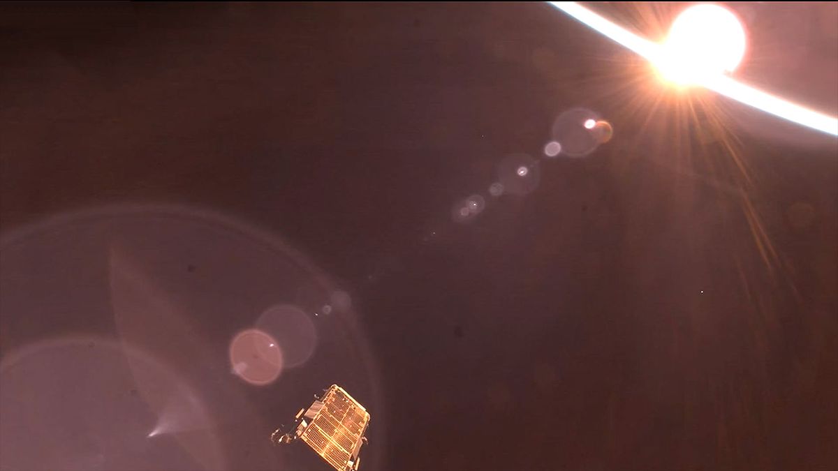 A satellite (lower left of the center) is seen after deployment in a orbital sunrise light