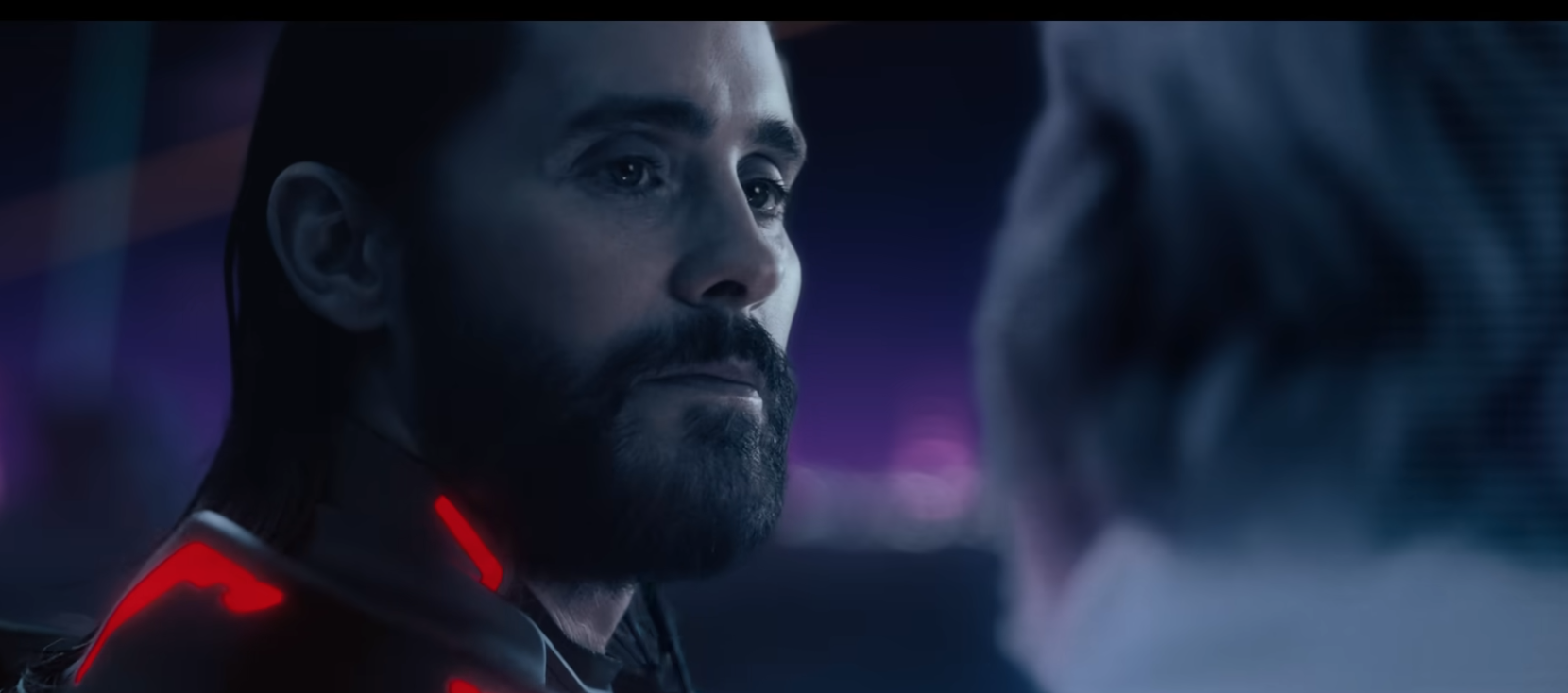 A bearded man with a glowing red spacesuit speaks to a white-haired figure offscreen