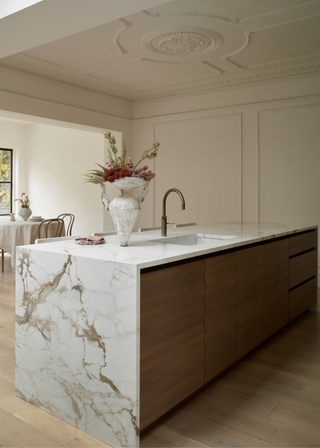 Beautiful kitchen with ceiling moulding and a waterfall marble kitchen island