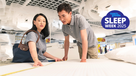 A man and a woman wearing grey clothes looking at a white mattress in a store