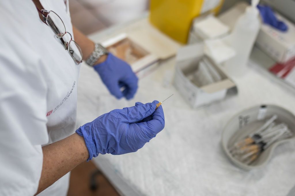 Nurse holding needle.