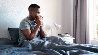Man in bed suffering from allergies