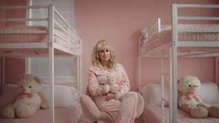 Tonia Haddix holding a teddy bear in a pink room sitting in the middle of two bunk beds with teddies.