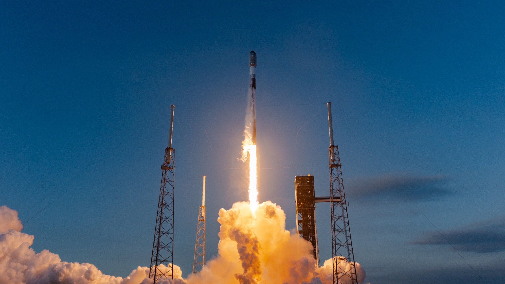 a black and white rocket launches into a blue sky