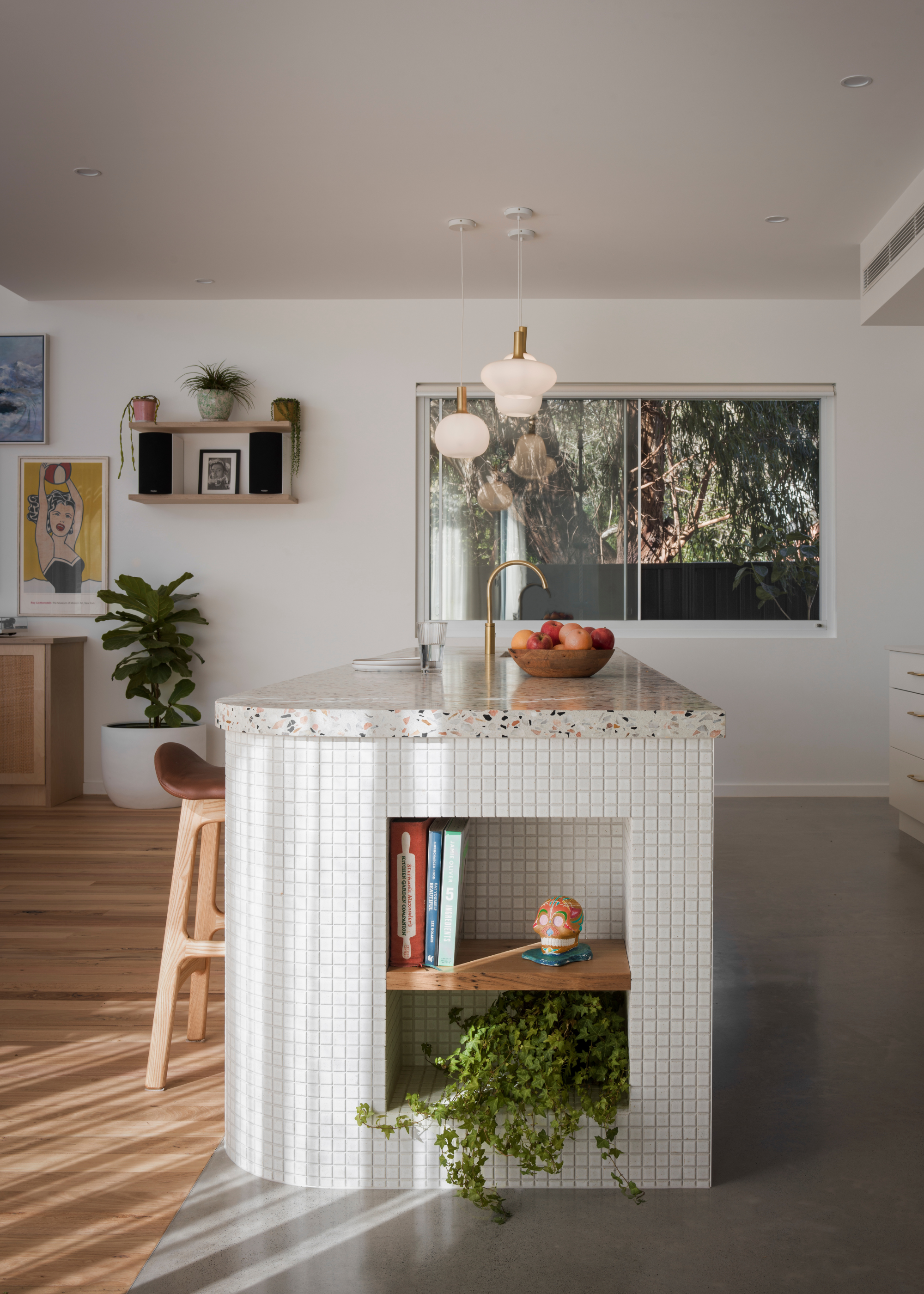 A tiled kitchen island with a stone counter and a potted trailing plant in a nook