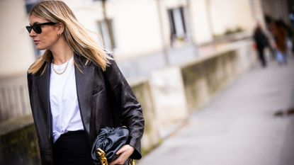 Camille Charriere, wearing white t-shirt, black pants, black leather blazer and black Bottega Veneta bag, is seen outside Mugler, during Paris Fashion Week