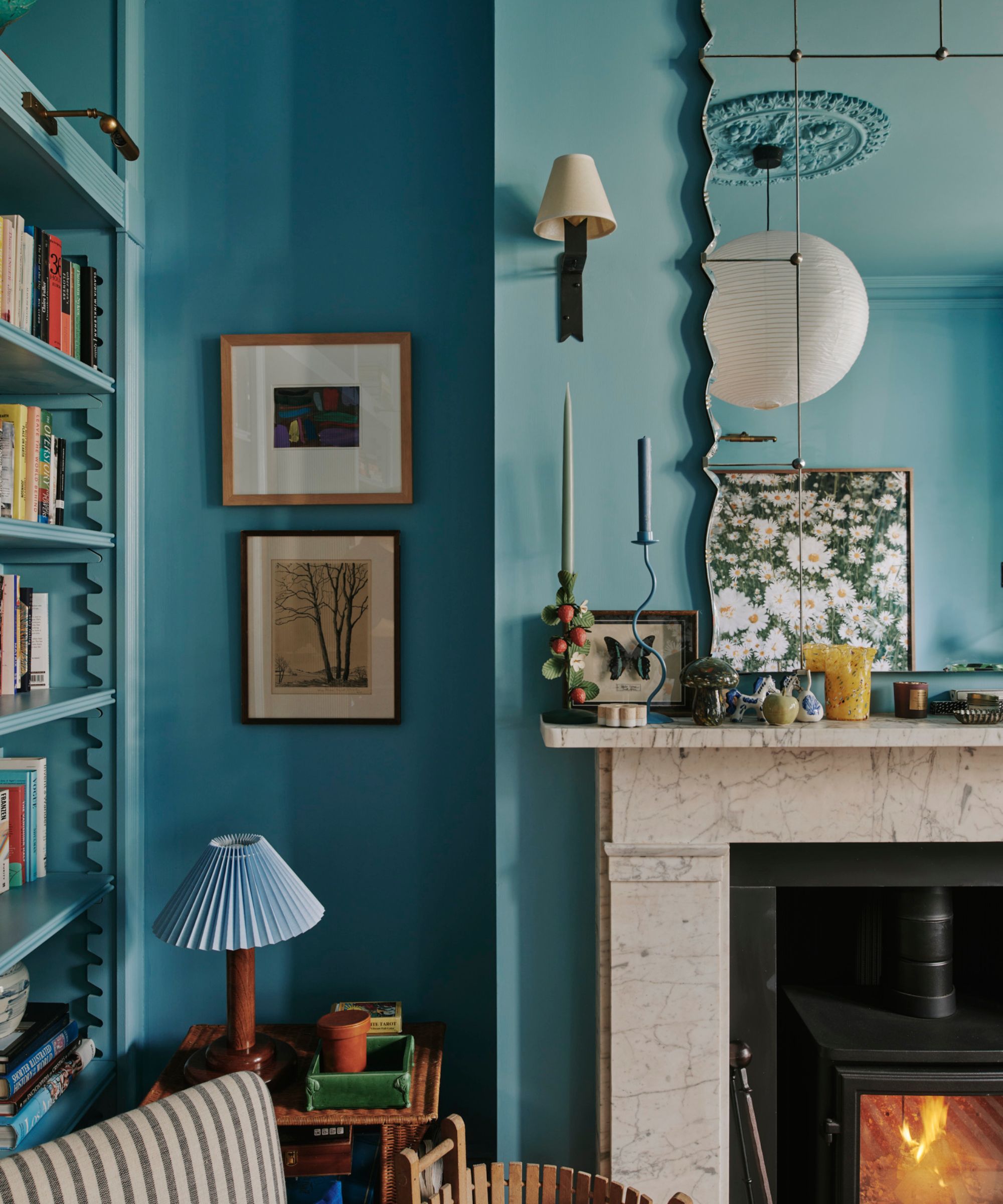 Blue painted walls with marble fireplace, wood burner, large mirror, reading nook with books