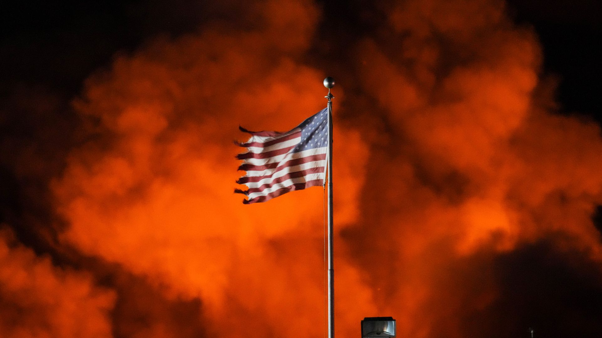 
                                An American flag waves in the wind as a fire breaks out at the SBS Technologies warehouse in Jenkintown, Pennsylvania
                            