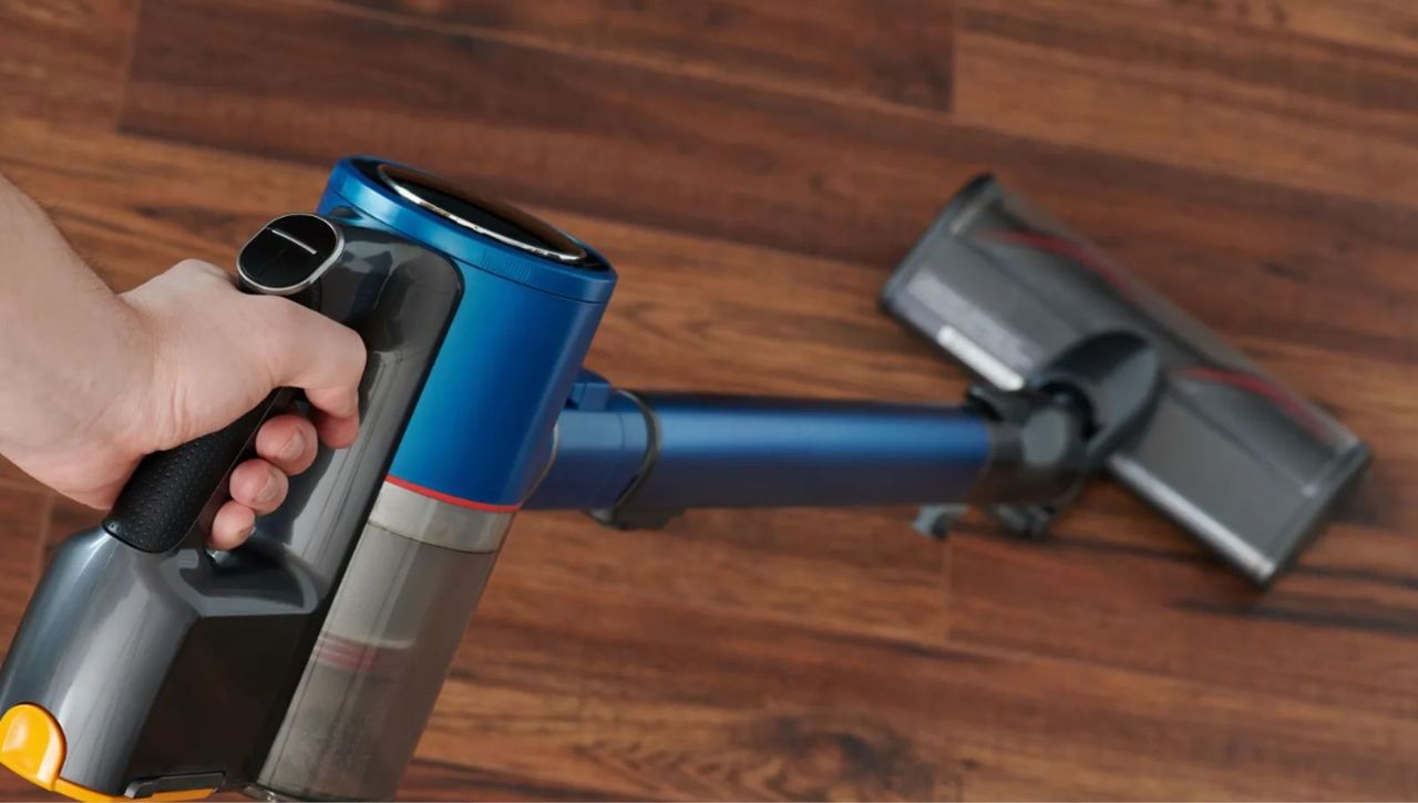 Blue and black cordless stick vacuum on hardwood floor