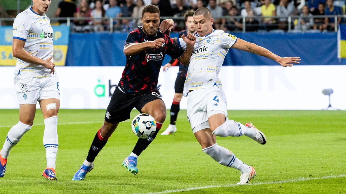 Rangers&#039; Cyriel Dessers (L), black shirt and black shorts, and Dynamo&#039;s Denys Popov, white shirt and white shorts, go shoulder to shoulder for the ball in the Rangers vs Dynamo Kyiv live stream.