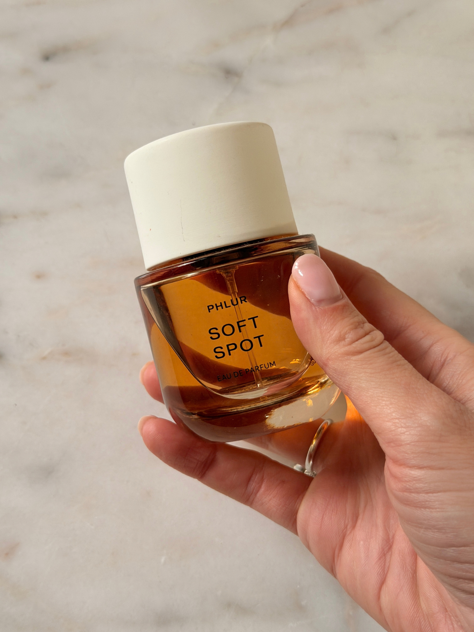 Freelance beauty editor Grace Day holding a bottle of Phlur Soft Spot Eau de Parfum