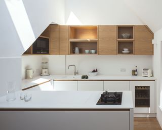 A U-shaped kitchen with white cabinets below wooden cabinets and open shelving