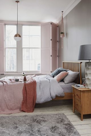 Pink bedroom with pink shutters and wooden bed