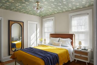 A bedroom in all-white with yellow bedding