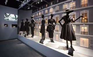 A catwalk with mannequins in black which bears a backdrop of the original Avenue Montaigne store
