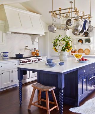 kitchen with blue and white cabinets and island hanging pans and dark wood floor