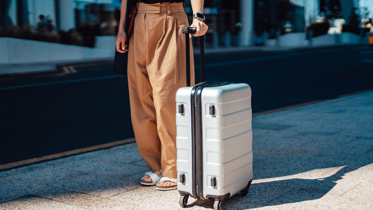 Low section of young woman walking with suitcase. City break. Business travel. Bleisure.