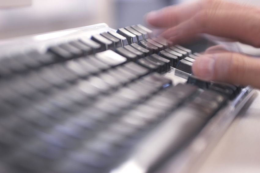 A person types on a computer keyboard.