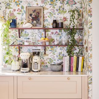 Magnet pink kitchen with floral wallpaper behind open shelving.