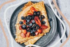 Pancakes on a plate covered in a variety of berries