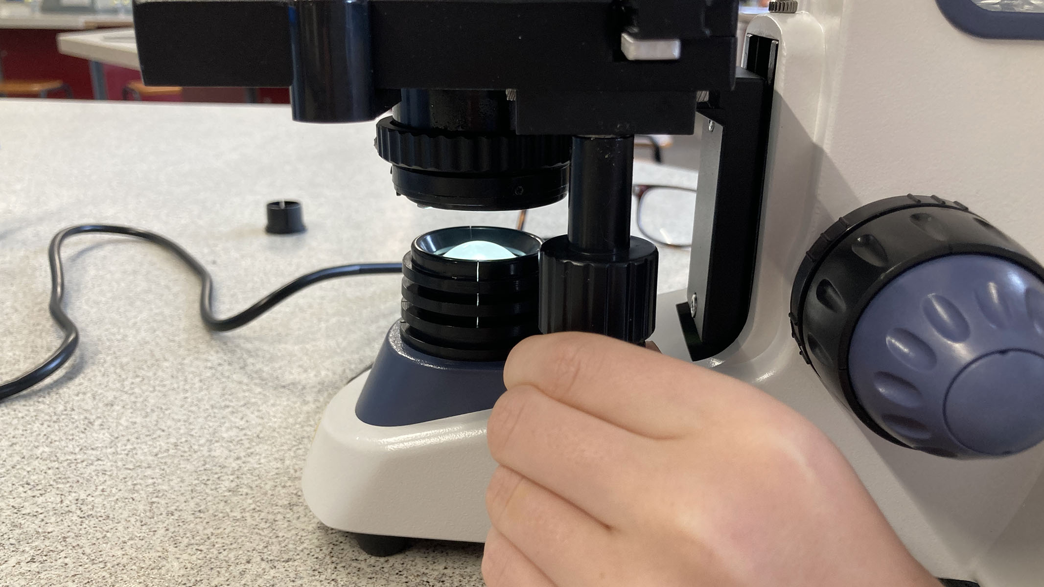 Person operates the mechanical stage of the microscope