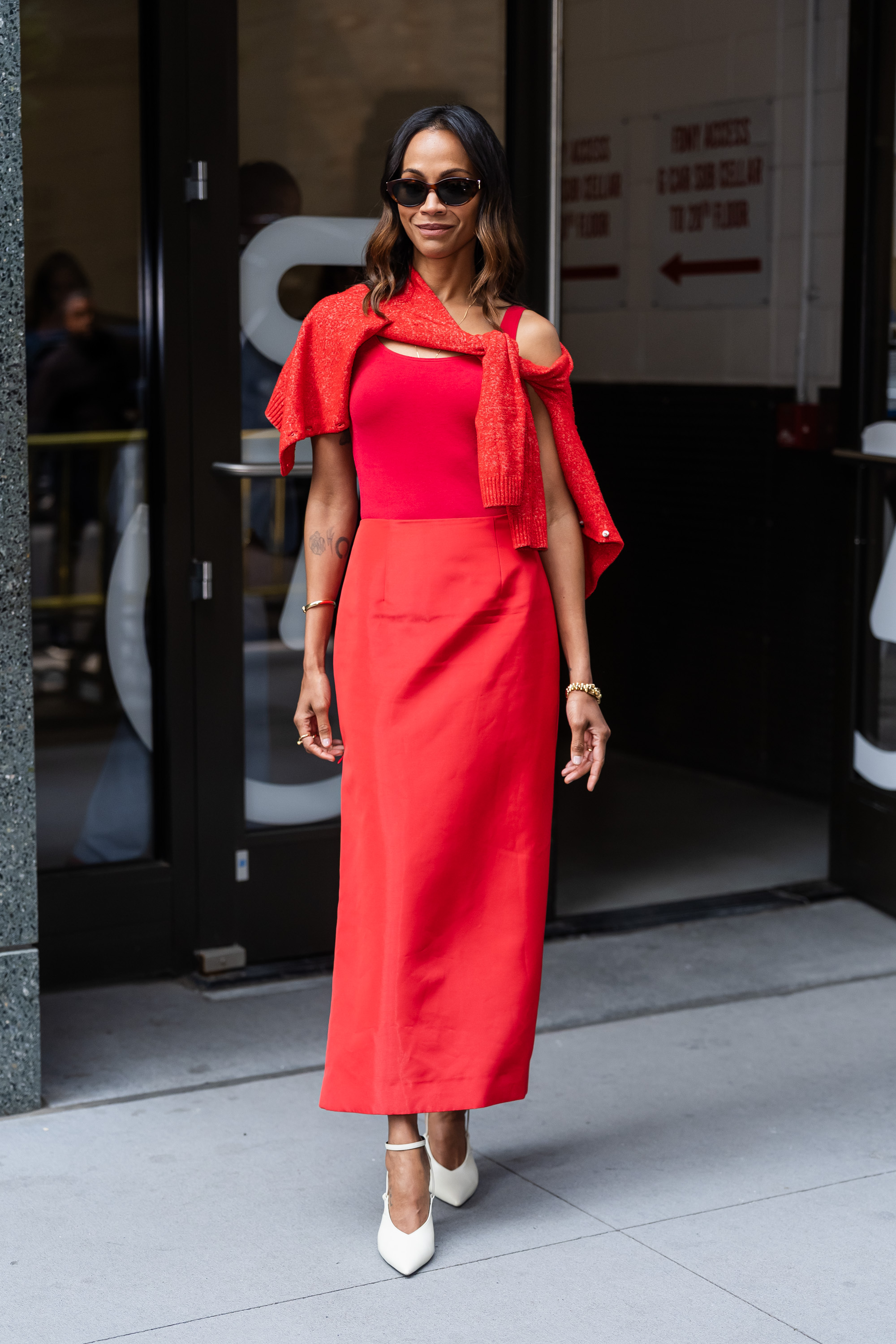 Zoe Saldaña sports a cherry red skirt set and a matching sweater in NYC.