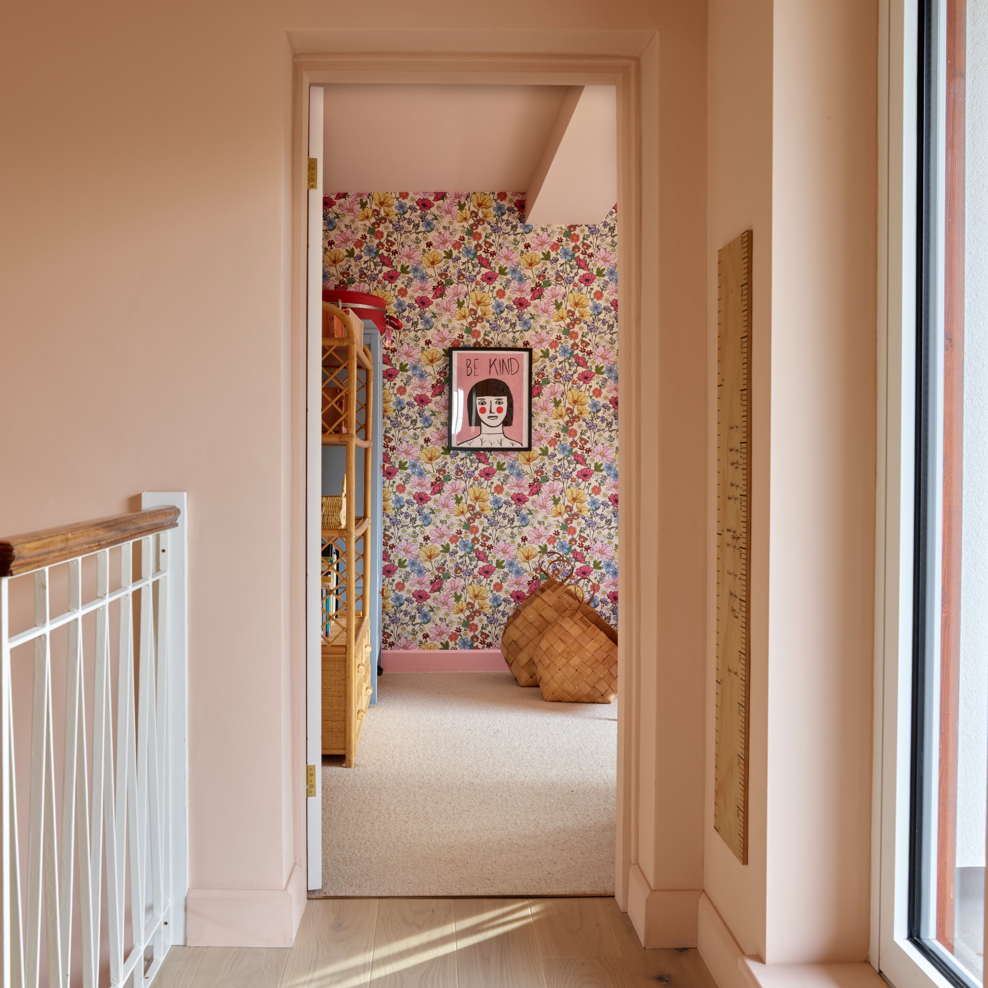 A colour-drenched hallway painted in pink leading to a girl's bedroom