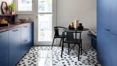 Image of a white kitchen with bright blue cabinetry and black and white Palladiana terrazzo flooring.