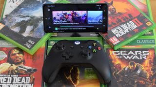An image of an Xbox controller, smartphone running Xbox Game Pass on top of some Xbox games