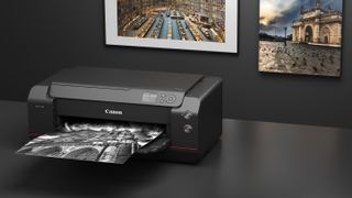 Canon ImagePrograf Pro-1100 on a black desk, printing out a photograph, with two printed photos mounted on the wall