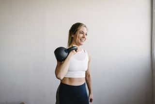 A woman holding a kettlebell up to her shoulder