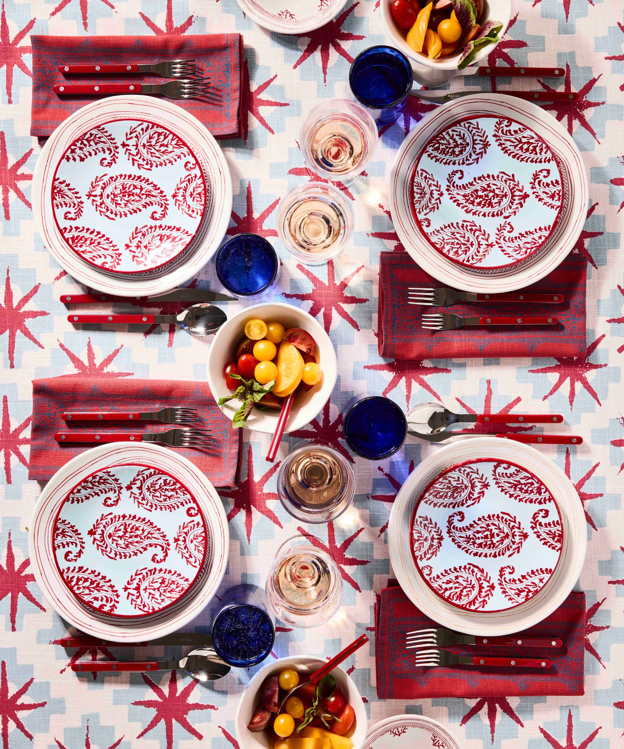 Red white and blue table setting with bowls of tomatoes in the middle