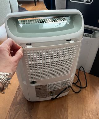 hand removing white back panel of dehumidifier
