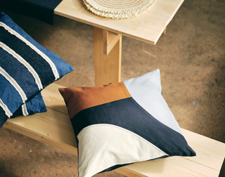 A asymmetrical patterned cushion on a wooden bench