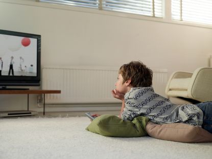 Boy lying on floor at home watching TV