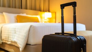 Suitcase next to a bed in a hotel