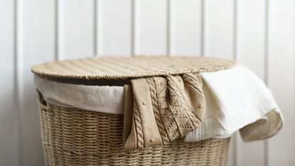 A laundry basket with two tops hanging out 