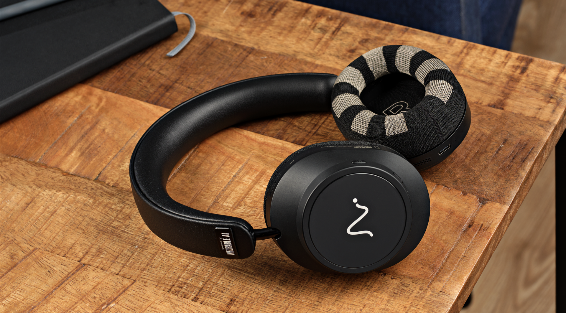Neurable One headphones on a wooden desk, or on a black background, showing the ear cups