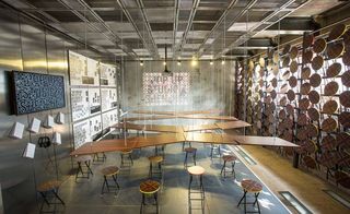 sea of tables suspended from a ceiling grid by moveable steel rods and an arrangement of stools