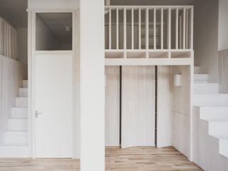 Bankside Loft by EBBA with white staircases right and left leading to an upper area.