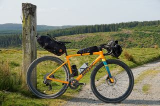 The BMC Kaius with Restrap saddlebag and Ortlieb's Handlebar Pack QR attached, leaning up against a post on the Trans Cambrian Way