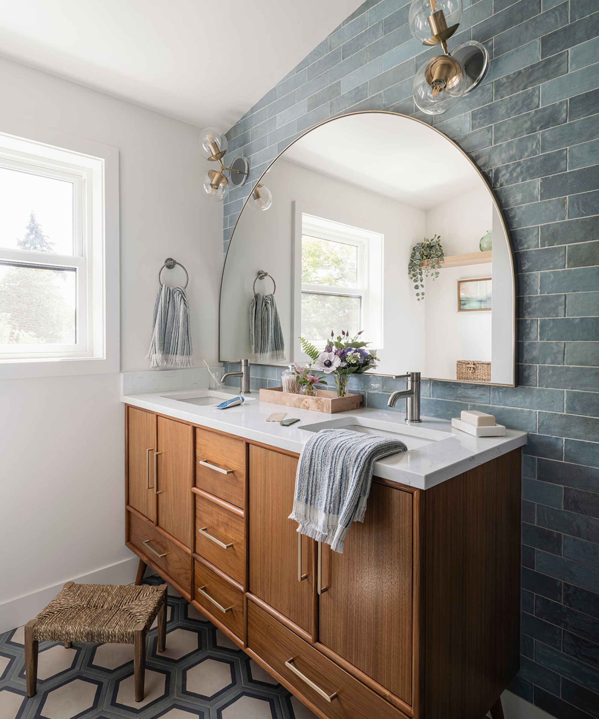 A bathroom with a wooden vanity, blue wall tiles, and walls painted in Sherwin-Williams Greek Villa