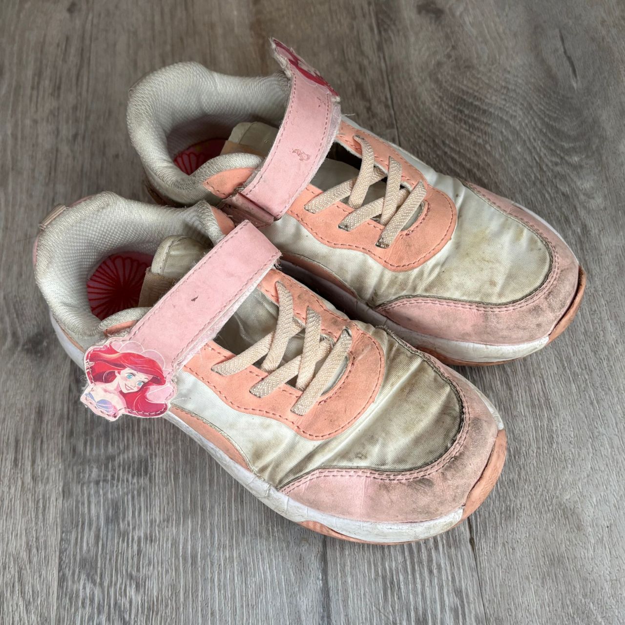 Pink and white pair of kids's trainers on grey flooring