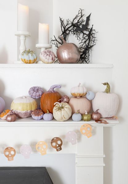 Mixture of pumpkins decorated with metallic paint on a mantel with skull garland
